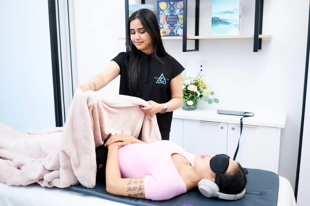 An Ageless Living practitioner settling a resting client in for a wellness session